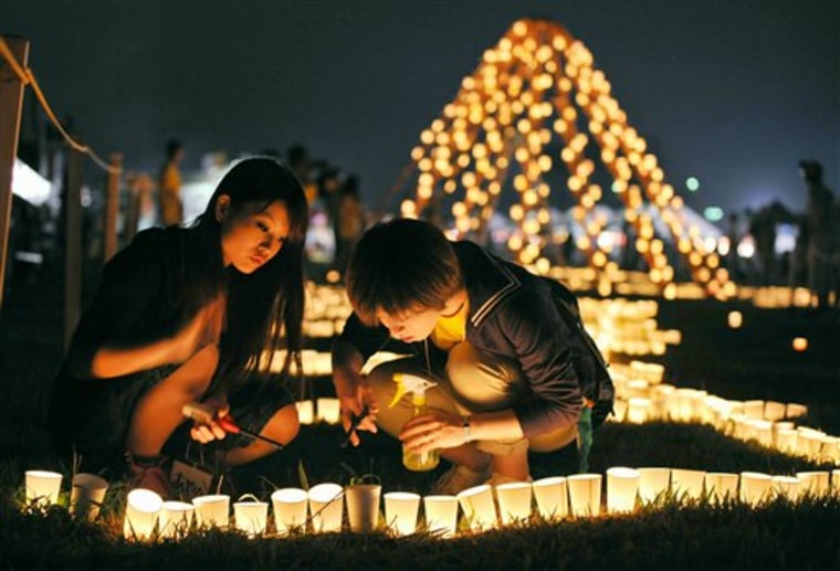 Local residents light a candle at a park during a memorial event marking six months after the March 11 earthquake and tsunami in Iwanuma city, Miyagi prefecture, Sunday, Sept. 11, 2011. As the world commemorates the 10th anniversary of the World Trade Center attacks, Sunday is doubly significant for Japan. It marks exactly six months since the disasters.